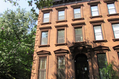 Ejemplo de fachada de casa roja clásica de tres plantas con revestimiento de estuco