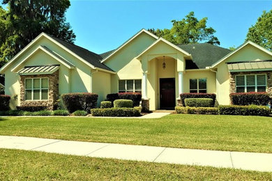 Inspiration for a large timeless yellow two-story stucco exterior home remodel in Orlando with a shingle roof
