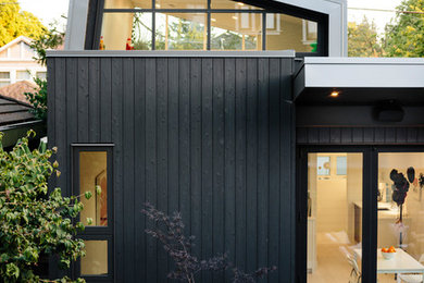 Aménagement d'une petite façade de maison noire contemporaine en bois à un étage avec un toit plat et un toit en métal.