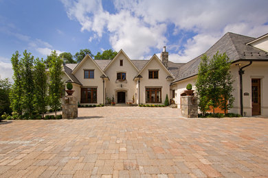 Пример оригинального дизайна: огромный, двухэтажный, бежевый дом в классическом стиле с облицовкой из цементной штукатурки и двускатной крышей