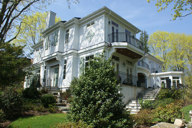 Imagen de fachada de casa blanca tradicional grande de dos plantas con revestimiento de madera