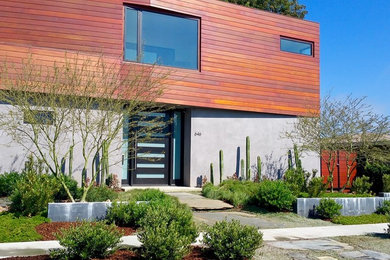 Imagen de fachada de casa gris actual grande de dos plantas con revestimientos combinados y tejado plano