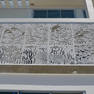 Exemple d'une grand façade de maison blanche bord de mer à un étage avec un toit plat et un toit en métal.