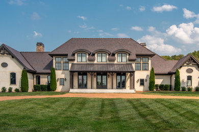 Example of a large french country beige two-story house exterior design in Nashville with a mixed material roof