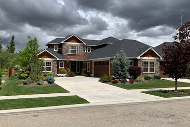Imagen de fachada de casa de estilo americano grande de dos plantas con revestimientos combinados, tejado de varios materiales y tejado a dos aguas