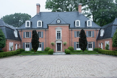 Cette photo montre une façade de maison chic en brique à un étage avec un toit à quatre pans.