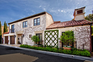 This is an example of a beige mediterranean two floor house exterior in Orange County.