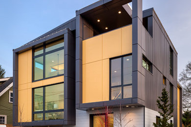 Immagine della facciata di una casa grigia contemporanea a piani sfalsati di medie dimensioni con rivestimento in metallo e copertura in metallo o lamiera