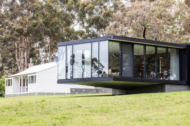 Свежая идея для дизайна: стеклянный, черный частный загородный дом в стиле модернизм - отличное фото интерьера