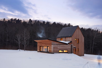 Imagen de fachada de casa marrón rústica pequeña de dos plantas con revestimiento de madera, tejado a dos aguas y tejado de metal