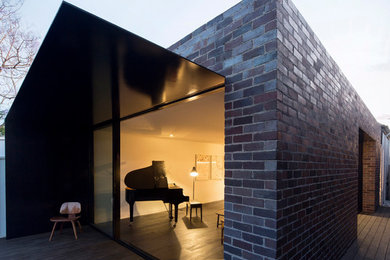 Diseño de fachada negra minimalista pequeña de una planta con revestimiento de ladrillo y tejado plano