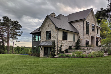 Example of a large farmhouse multicolored two-story stone and board and batten exterior home design in Toronto with a mixed material roof and a black roof