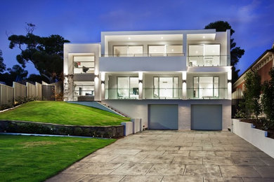 Cette photo montre une grande façade de maison blanche moderne en béton à un étage avec un toit plat.
