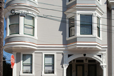 Large and gey victorian house exterior in San Francisco with three floors and a hip roof.