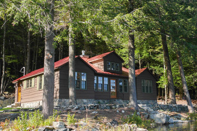 Ejemplo de fachada de casa marrón rústica de tamaño medio de una planta con revestimiento de madera, tejado a dos aguas y tejado de metal