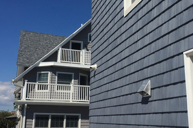 Foto de fachada de casa azul marinera con revestimiento de vinilo y tejado de teja de madera