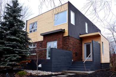 Imagen de fachada de casa negra moderna de tamaño medio de dos plantas con tejado plano y revestimientos combinados