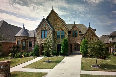 Inspiration for a large 1950s beige two-story stone house exterior remodel in Dallas