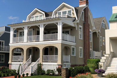 Ejemplo de fachada de casa beige marinera grande de tres plantas con revestimiento de madera, tejado a doble faldón y tejado de varios materiales