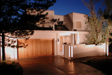 Diseño de fachada moderna de dos plantas con revestimiento de estuco y tejado plano