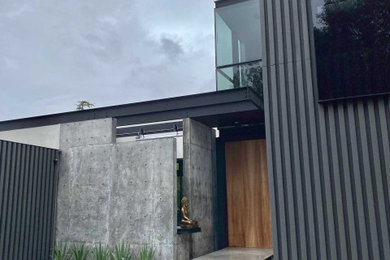 Ejemplo de fachada de casa gris contemporánea grande de dos plantas con revestimientos combinados, tejado plano y tejado de metal