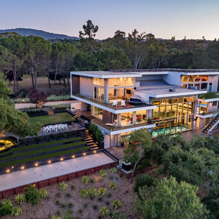 Imagen de fachada de casa gris, contemporánea, extra grande, de tres plantas, con revestimiento de hormigón, tejado plano y tejado de teja de barro