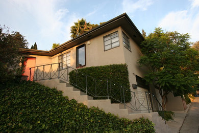 Inspiration for a large contemporary beige split-level stucco exterior home remodel in Los Angeles with a metal roof