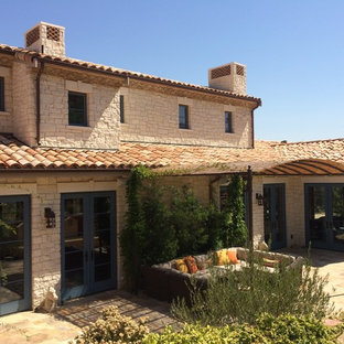 Photo of a large two-storey beige house exterior in San Francisco with stone veneer, a gable roof and a tile roof.