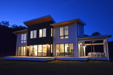 Imagen de fachada de casa gris y blanca actual de tamaño medio de dos plantas con revestimiento de metal, techo de mariposa, tejado de metal y tablilla