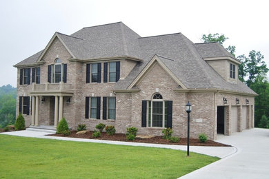 Large elegant beige two-story brick exterior home photo in Other