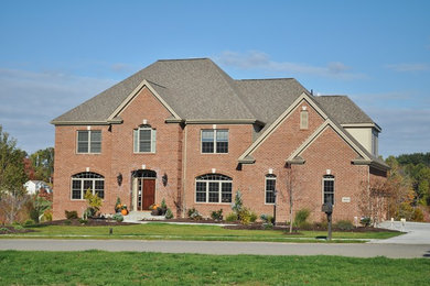 Large elegant red two-story brick exterior home photo in Other