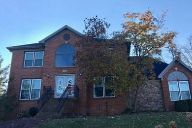 Zweistöckiges Haus mit Backsteinfassade, roter Fassadenfarbe und Schindeldach in Louisville