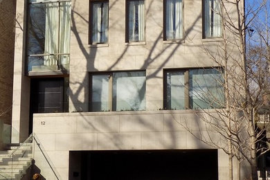 Foto della facciata di una casa beige contemporanea a tre piani con rivestimento in pietra e tetto piano