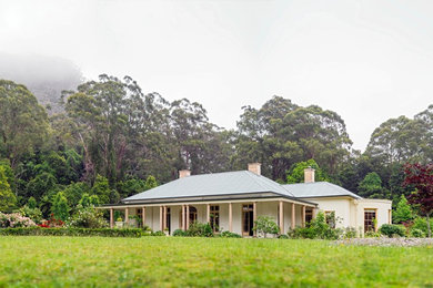 Imagen de fachada beige tradicional de tamaño medio de una planta con revestimiento de estuco y tejado a cuatro aguas