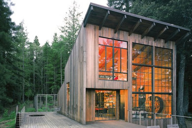 Aménagement d'une grande façade de maison beige moderne en bois à niveaux décalés avec un toit en appentis.