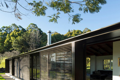 Idee per la villa piccola marrone moderna a un piano con rivestimento in pietra, copertura in metallo o lamiera e tetto a capanna