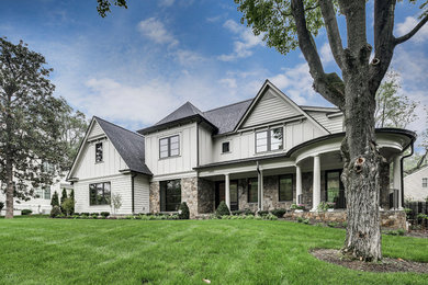 Imagen de fachada de casa gris actual grande de tres plantas con revestimientos combinados y tejado de teja de madera