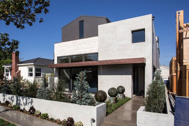 Modelo de fachada de casa gris actual de tamaño medio de dos plantas con revestimientos combinados, tejado a dos aguas y tejado de metal