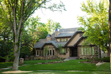 Inspiration for a large timeless beige two-story stucco exterior home remodel in Calgary with a clipped gable roof