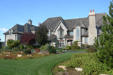 Inspiration for a huge timeless gray two-story stone exterior home remodel in Chicago with a hip roof