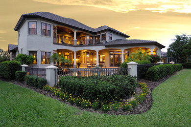 Example of a large tuscan beige two-story stucco house exterior design in Tampa with a hip roof and a tile roof