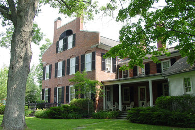 Cette image montre une grande façade de maison rouge traditionnelle en brique à deux étages et plus avec un toit à deux pans.