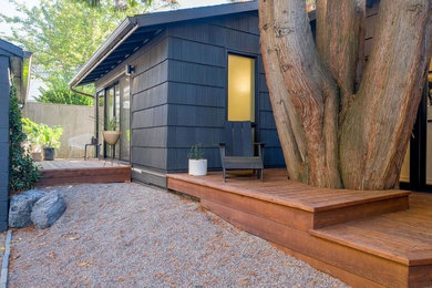 Diseño de fachada de casa gris de estilo zen de una planta con revestimiento de madera, tejado a dos aguas y tejado de teja de madera
