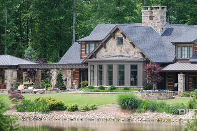 Foto de fachada marrón rústica grande de dos plantas con revestimiento de piedra y tejado a dos aguas