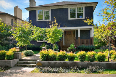 Large arts and crafts blue two-story wood house exterior photo in Seattle with a hip roof and a shingle roof