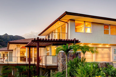 Foto della facciata di una casa beige tropicale a due piani con rivestimento in stucco