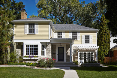 Mittelgroßes, Zweistöckiges Klassisches Einfamilienhaus mit Faserzement-Fassade, gelber Fassadenfarbe, Walmdach und Schindeldach in Chicago