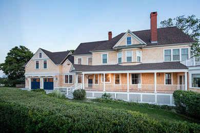 Photo of a large beach style house exterior in Boston with three floors, wood cladding and a pitched roof.