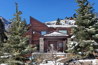 Example of a large mountain style brown three-story house exterior design in Other with a metal roof and a brown roof