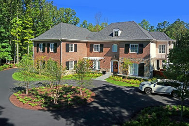 Foto della villa ampia multicolore a due piani con rivestimento in mattoni, tetto a padiglione e copertura a scandole
